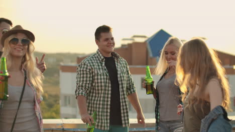 Young-American-people-move-in-a-dance-on-the-roof.-They-have-fun-smile-and-drink-beer.